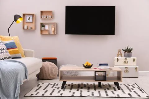 Modern TV, comfortable sofa and decor elements in living room Stock Photos