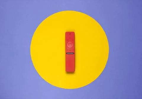 Modern tv remote in a case on colored paper background with yellow circle in  Stock Photos