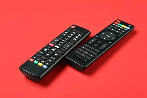 Modern TV remote controls on red background Stock Photos