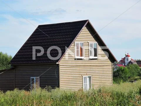 Modern Two-Storeyed Summer Cottage Against A Blue Sky