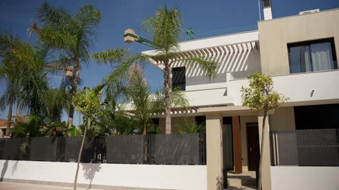 Modern two-story home with clean facade, private garden of palm trees, slee.. Stock Footage 321199247