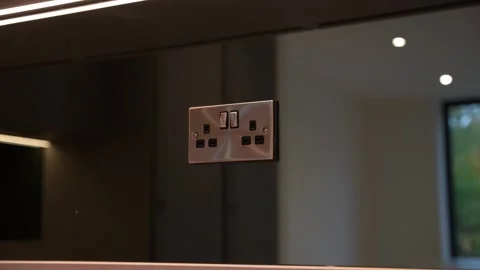 Modern UK Plug Socket on Sleek Mirrored Kitchen Backsplash Stock Footage 322890039