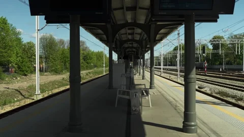 Modern Urban Train Platform on a Sunny Day with Empty Benches and Passing Train Stock Footage 308686560