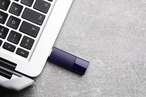Modern usb flash drive attached into laptop on light grey table, flat lay. .. Stock Photos