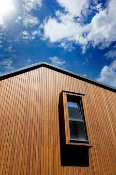 Modern vertical window on the facade of the house with wooden plank trim Stock Photos
