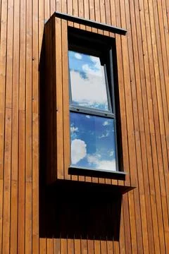 Modern vertical window on the facade of the house with wooden plank trim Stock Photos