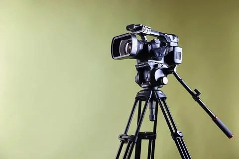 Modern video camera with tripod on light olive background, space for text Stock Photos
