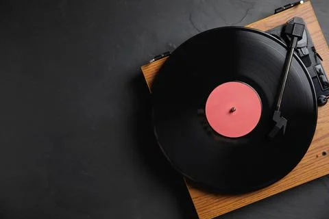 Modern vinyl record player with disc on black background, top view. Space for Stock Photos