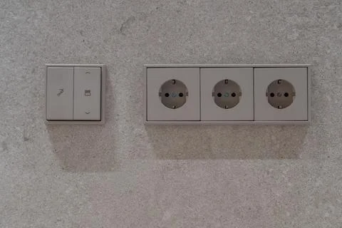 Modern wall electrical sockets and light switches on textured surface Stockfoto's