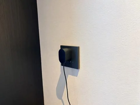 Modern Wall Socket with Plugged-in Black Charger and Cable 스톡 사진