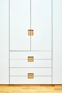 Modern wardrobe with finger pull design. Wooden wardrobe with light gray cabi Stock Photos