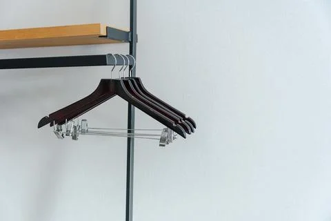 Modern wardrobe rail with empty black clothes hangers under wooden shelf, o.. Stock Photos