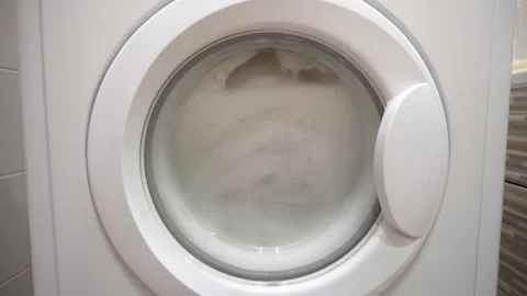 Modern washing machine with laundry inside, view through the glass door Stock Footage 335469310
