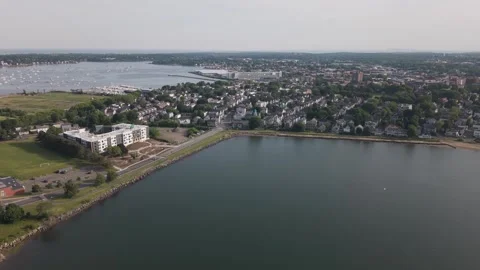 Modern white apartment complex sits beside soccer field and waterfront road in Stock Footage 341675838