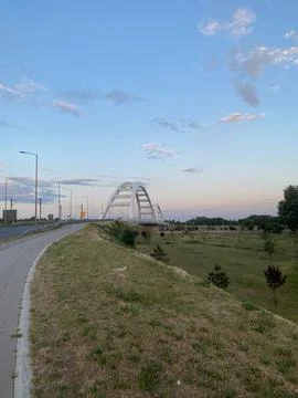 Modern white arch bridge spanning landscape in twilight sky Stock Photos