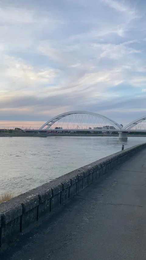 Modern white arched bridge over wide Danube river at dusk Stock Footage 339480140