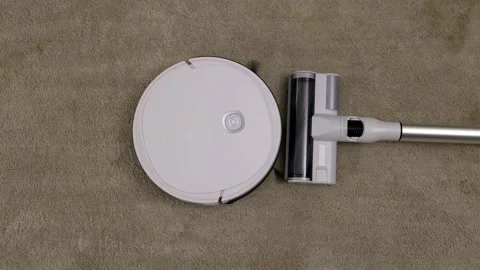 A modern white automatic robot vacuum sweeps the floor in the room. 스톡 동영상 202010108