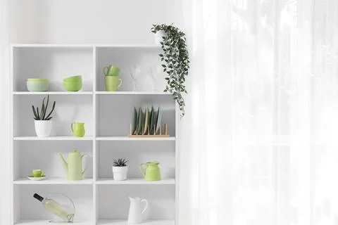 Modern white bookshelf with green kitchenware and home decor items, minimalis Stock Photos