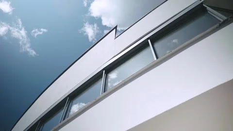 Modern White Building Facade with Panoramic Windows Against Blue Sky and Clouds 스톡 동영상 326341548