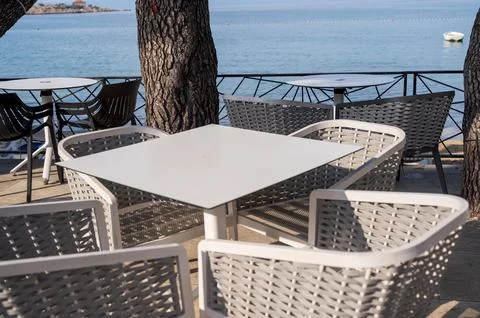 Modern white cafe table and comfortable wicker chairs on a coastal terrace with Stock Photos