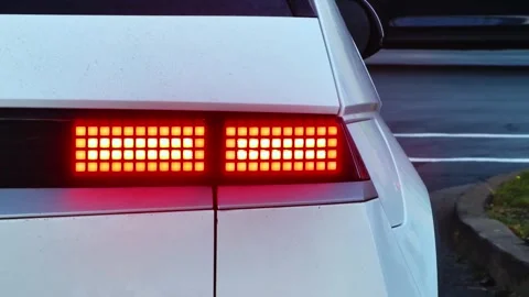 Modern White Car With Red Tail Light Waiting At Traffic Light In City Turn Lane Stock Footage 319869864