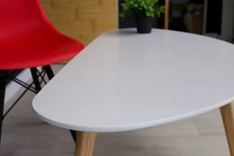 Modern white coffee table with red chair and green plant in a bright room Stock Photos