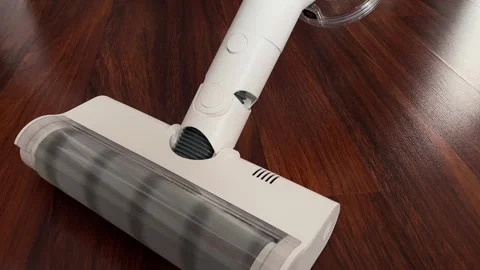 A modern white cordless vacuum cleaner effectively cleans a wooden floor. A clos Stock Footage 340194568