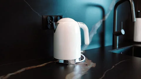 Modern white electric kettle with blue LED light boiling water on kitchen counte Stock Footage 340342933