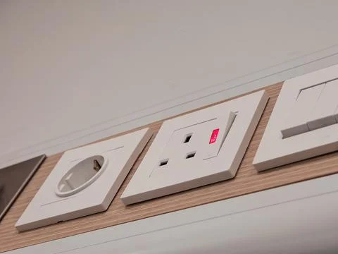 Modern White Electrical Wall Sockets on Wood Panel With Red Indicator Light Фото