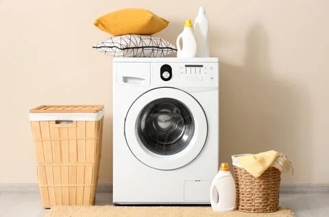 Modern white front-load washing machine with laundry baskets and detergent bo Stock Photos