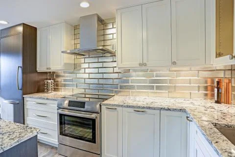 Modern white kitchen design with silver backsplash, white shaker cabinets and Stock Photos