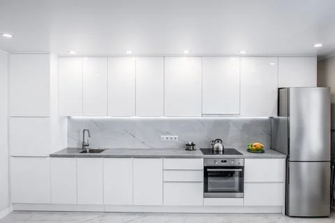 Modern white kitchen with many cabinets and appliances Stock Photos
