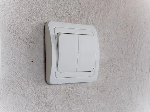 Modern white light switch on gray concrete wall Stock Photos