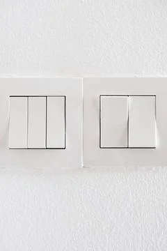 Modern white light switch panels on a clean wall Stock Photos