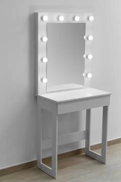 Modern white makeup dressing table with mirror and backlight on a white wal.. Stock Photos