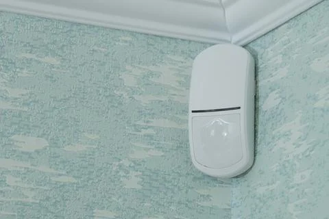 Modern white motion sensor on the wall in the room. Stock Photos