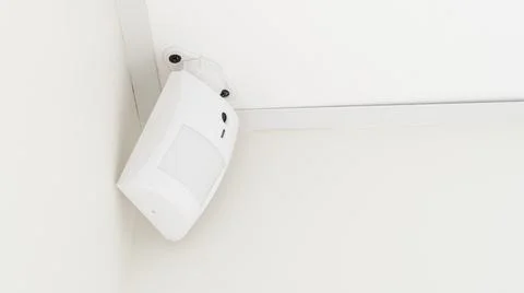 Modern white motion sensor on the wall in the room. Stock Photos