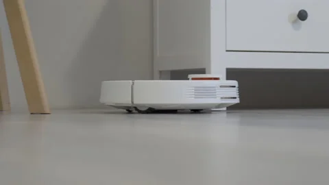 Modern White Robotic vacuum cleaner working house floor Stock Footage 220066853