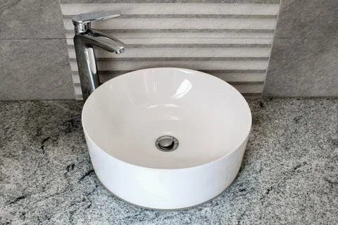 Modern white round shaped ceramic wash basin in the marble bathroom. Stock Photos