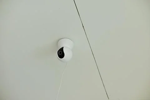 Modern white security camera on ceiling with wire Stock Photos