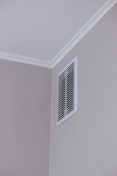 Modern white ventilation grill installed in the corner of a clean interior .. Stock Photos