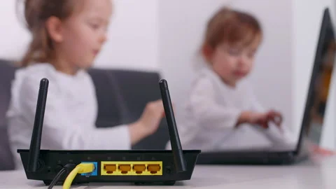 Modern wifi router on light table in the room. Two cute little girls typing o Vidéo 131786420