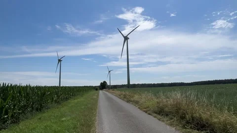 Modern wind turbine generating clean electricity against blue sky in rural lands Stock Footage 339631256