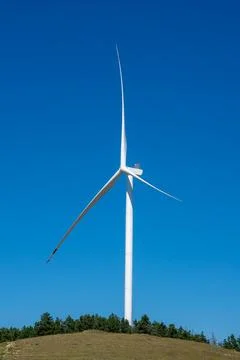Modern wind turbine generating clean energy against a clear blue sky Stock Photos