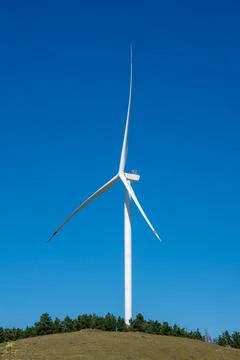Modern wind turbine generating clean energy against a clear blue sky Stock Photos