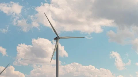 Modern Wind Turbine Head and Blades Spinning Smoothly with Puffy Clouds Behind Stock Footage 313544984