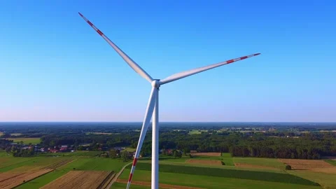 Modern wind turbine rotating over rural agricultural fields daytime Video stock 342593163