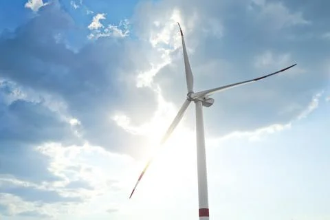 Modern windmill against sky with clouds, low angle view. Energy efficiency Stock Photos