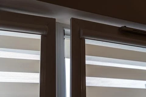 Modern window with elegant roller blinds partially opened, creating a Stock Photos