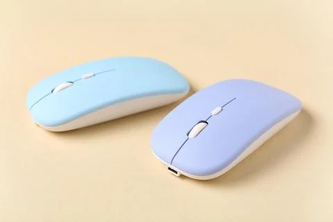 Modern wireless blue computer mouse devices on beige background Stock Photos